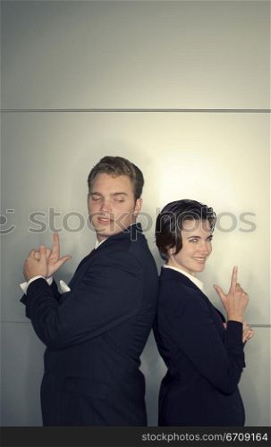 Business man and business woman stand back to back with their hands shaped like guns