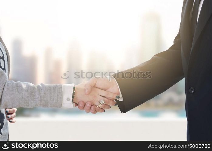 business man and woman handshake on successful meeting in front of the big city
