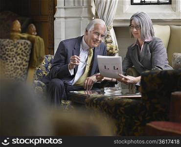 Business man and woman sitting indoors looking at documents