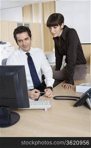 Business man and woman using computer at desk in office