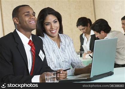 Business man and woman using laptop at conference meeting