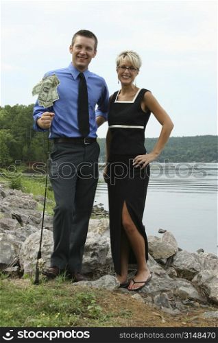 Business man and woman with money hanging from fishing pole.