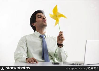 Business man at desk playing with pinwheel