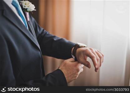 Business man buttoning at the wrist watch.. A man in a suit wears a watch on his arm 716.. A man in a suit wears a watch on his arm 716.