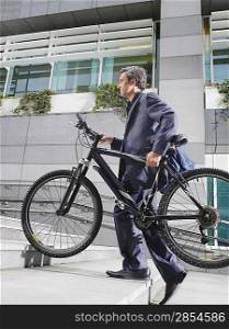 Business man carrying bicycle up steps side view