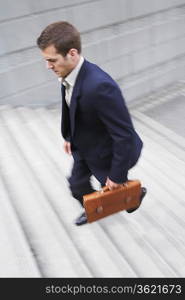 Business man carrying briefcase, ascending steps, elevated view