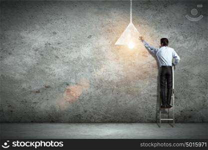Business man drawing lamp. Image of businessman drawing lamp on wall