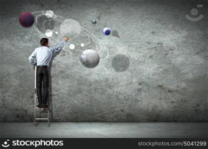 Business man drawing planets. Image of businessman drawing planets on wall