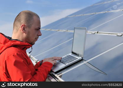 business man engineer using laptop at solar panels plant eco energy field in background