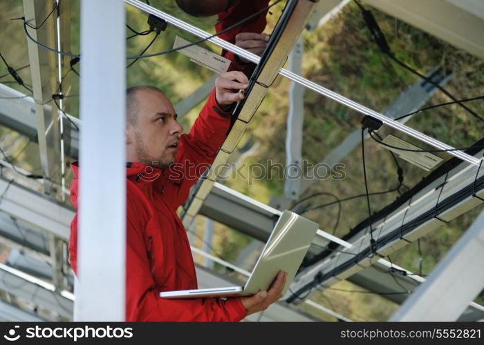 business man engineer using laptop at solar panels plant eco energy field in background