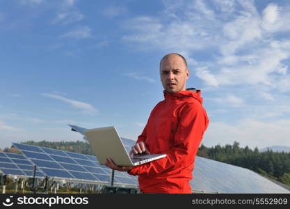 business man engineer using laptop at solar panels plant eco energy field in background