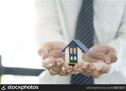 Business man hand hold the house model saving small house. House insurance.