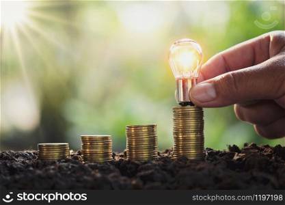 business man hand holding lightbulb money stack. idea saving energy and accounting finance concept