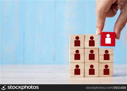Business man hand placing or pulling Red wooden block with white person icon on the building. People, Business, Human resource management, Recruitment, Teamwork, strategy and leadership Concepts