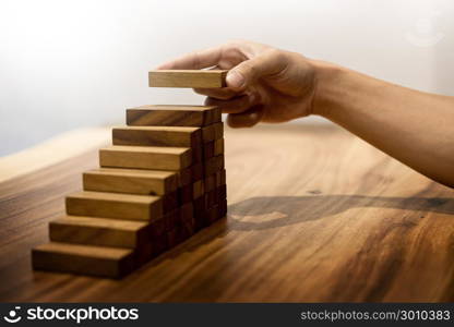 Business man hand put wooden blocks arranging stacking for development as step stair, Concept of growth and success plan.