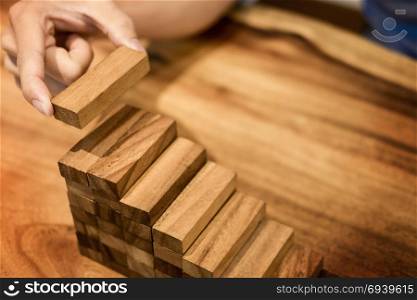 Business man hand put wooden blocks arranging stacking for development as step stair, Concept of growth and success plan.