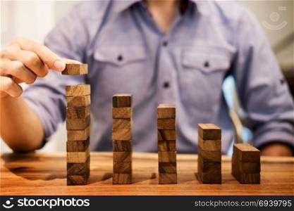 Business man hand put wooden blocks arranging stacking for development as step stair, Concept of growth and success plan.