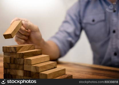 Business man hand put wooden blocks arranging stacking for development as step stair, Concept of growth and success plan.