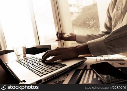 business man hand working on laptop computer on wooden desk as concept 