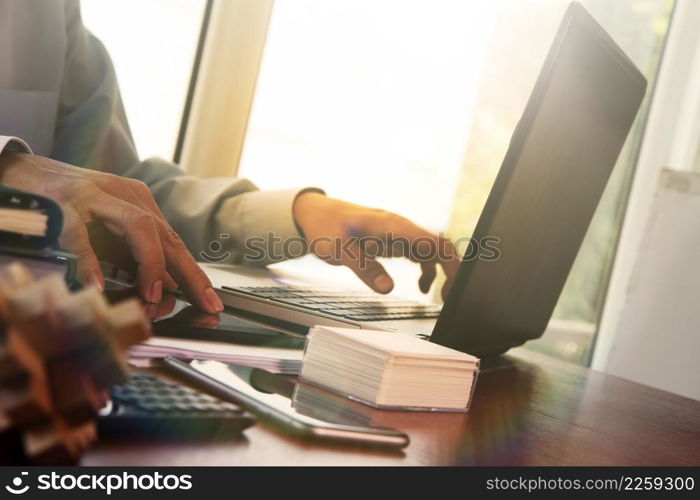 business man hand working on laptop computer on wooden desk as concept