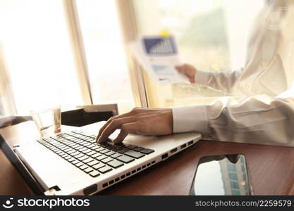 business man hand working on laptop computer on wooden desk as concept