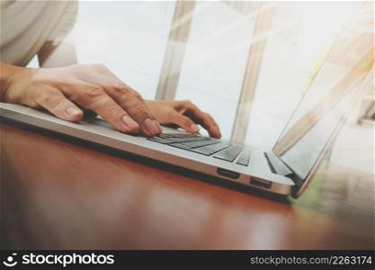 business man hand working on laptop computer on wooden desk as concept