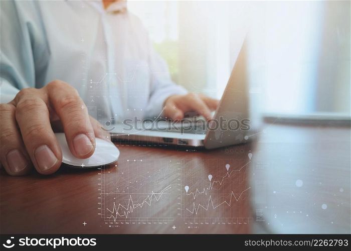 business man hand working on laptop computer on wooden desk with digital business layer effect diagram as concept