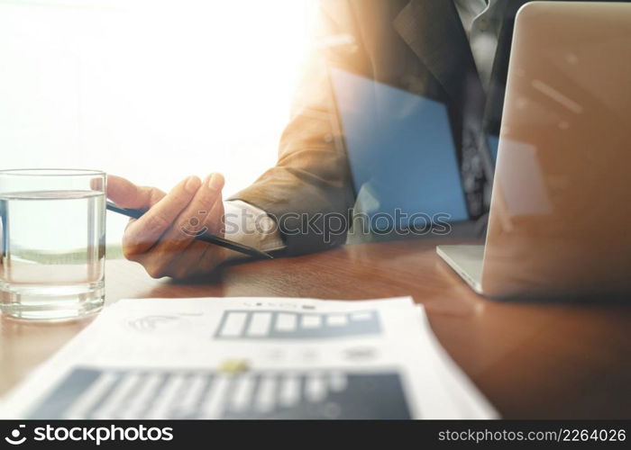 business man hand working on laptop computer with business graph information diagram on wooden desk as concept