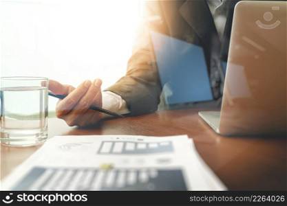 business man hand working on laptop computer with business graph information diagram on wooden desk as concept