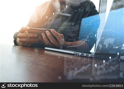 business man hand working on laptop computer with smart phone and business graph information diagram on wooden desk as concept