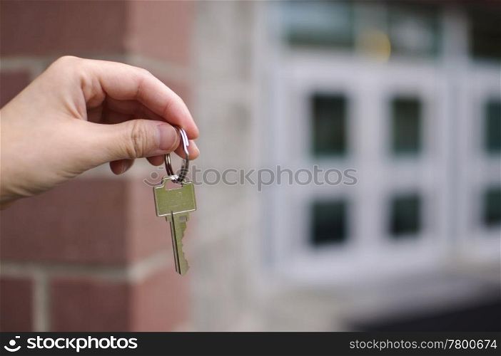 Business man handing key in front of building