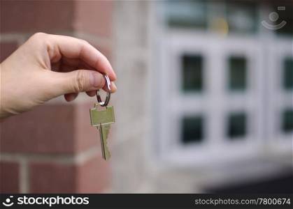 Business man handing key in front of building