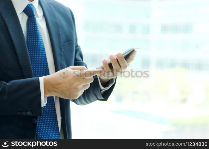 Business man hands using smart phone by windows with city view, inside office building background, businessman on phone