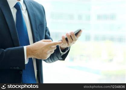 Business man hands using smart phone by windows with city view, inside office building background, businessman on phone