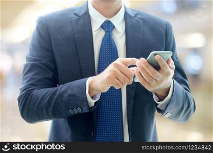 Business man hands using smart phone over blur office with bokeh light background, businessman on phone
