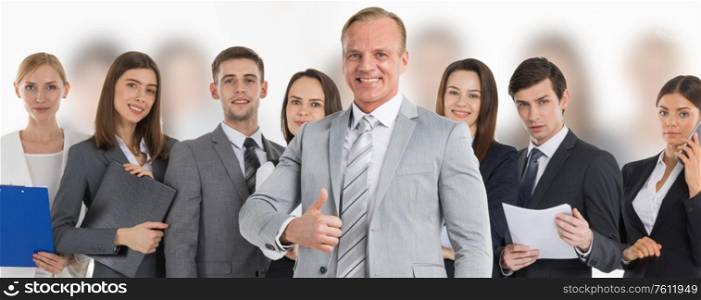 Business man hold hand with thumb up gesture, business man excited happy smile over group of businesspeople team background. Business leader and team