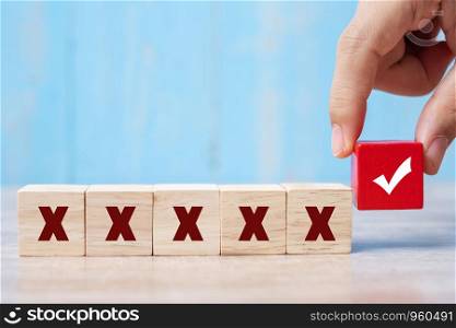business man holding Wood cubes block with Right symbol different from Wrong symbol on table background