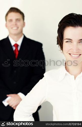 Business man in black suit and tie stands behind smiling woman in white clothes