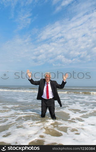 Business man in formal suit hands up standing in the sea
