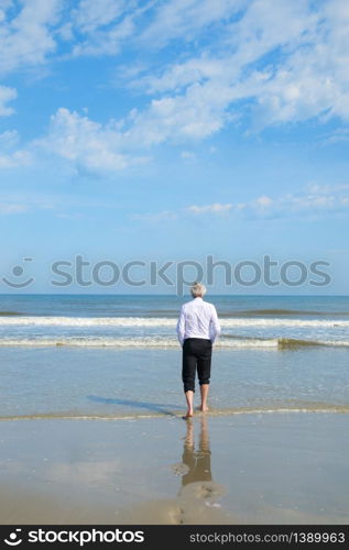 Business man in formal suit walking in the sea