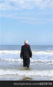 Business man in formal suit walking into the sea