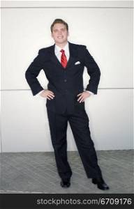 Business man in red tie and black suit standing in dynamic pose against a metallic background