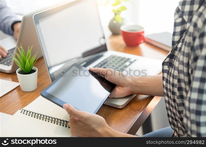 business man in suit sitting at table working on his laptop and looking at a document on the desk.
