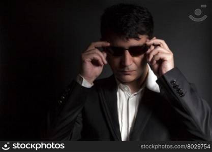 Business man in suit with sunglasses on a black background