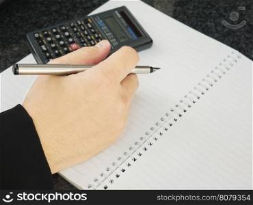 Business man is holding pen with empty note book working with calculator. Financial working concept.