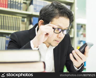 Business man is looking at his mobile phone in his office