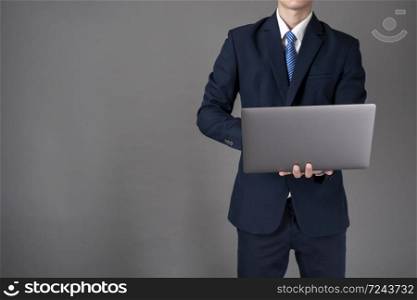 Business man is using laptop ,grey background in studio