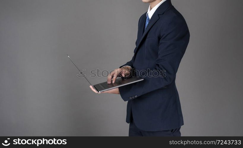 Business man is using laptop ,grey background in studio