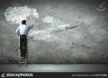 Business man on ladder. Businessman standing on ladder and pointing on picture on wall