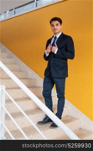 Business man on the stairs with a yellow wall behind